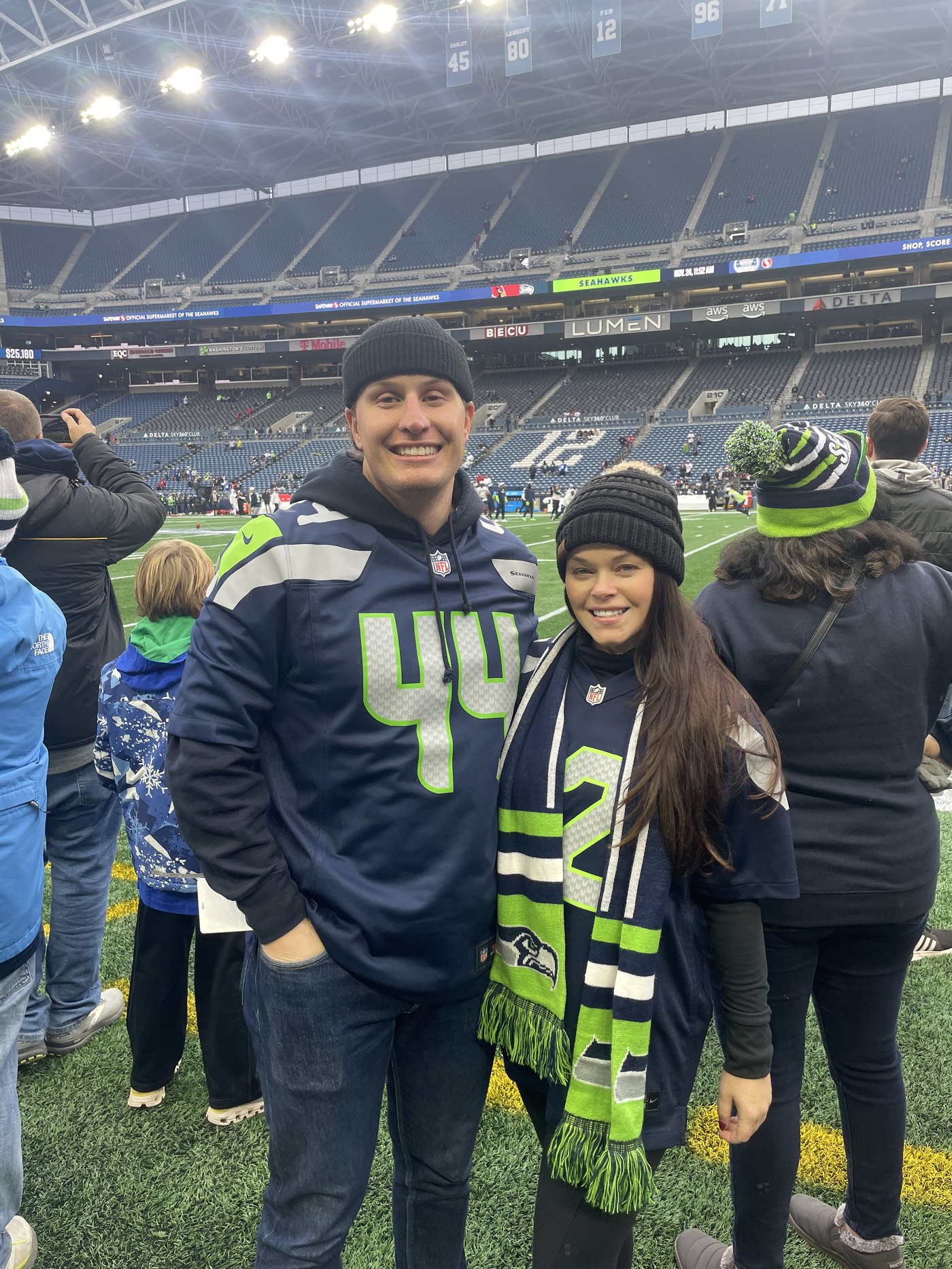 Sean and Brittany in Seahawks gear on the field at Lumen Field before a game