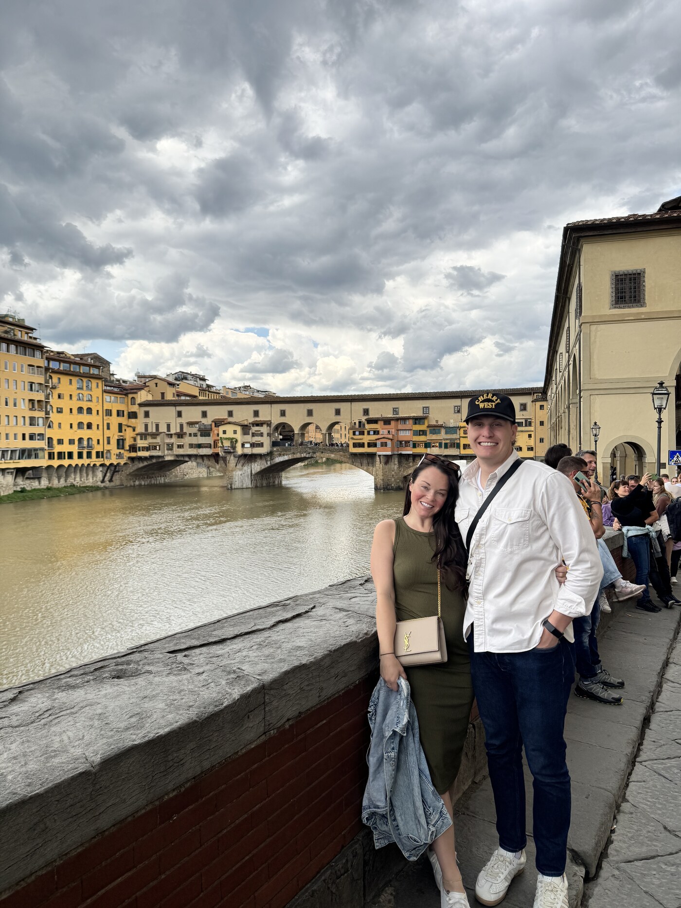 Sean and Brittany smiling along the Arno river with the Ponte Vecchio behind them in Florence